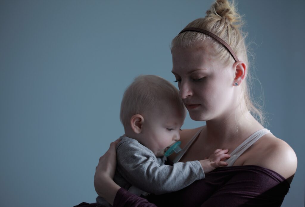 young mother holding her newborn baby in her arms and facing postpartum depression