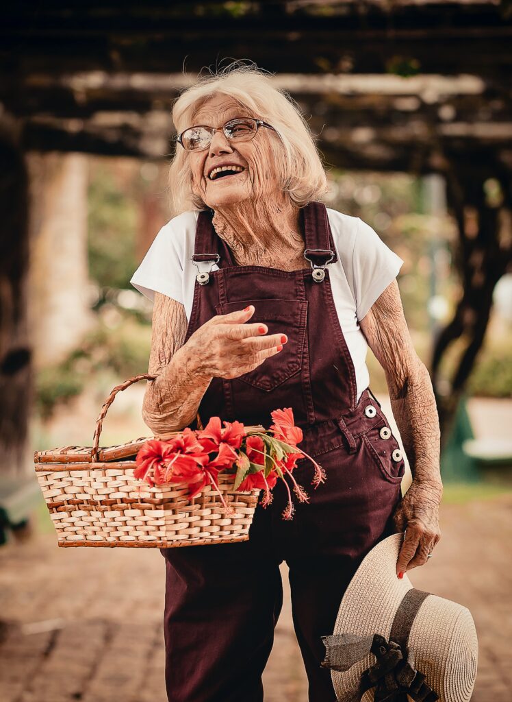 elderly woman carrying flower basket with open smile