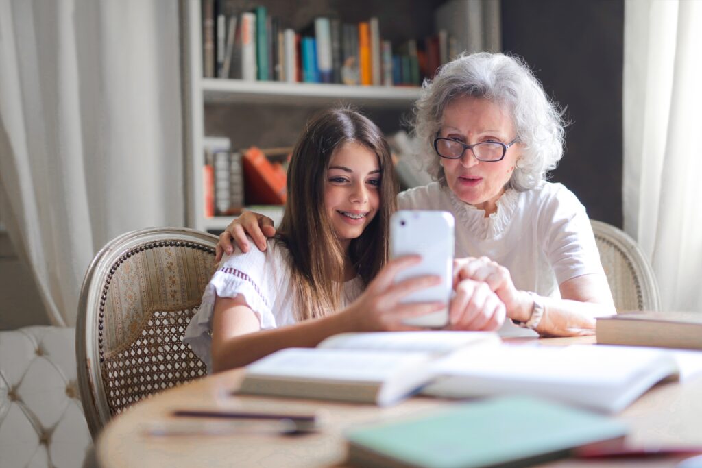 elderly woman with granddaughter looking at a phone together to understand senior mental health