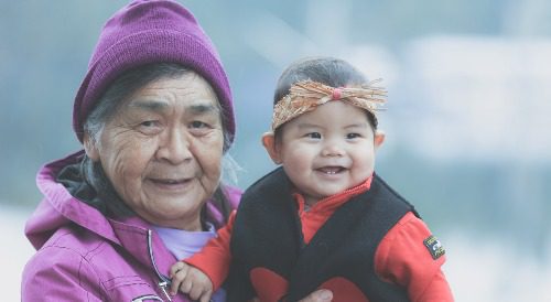 Indigenous elder and child smiling at camera.