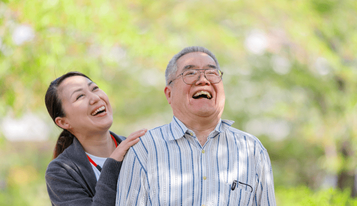 Пожилой азиатский мужчина и азиатский опекун смеются снаружи
